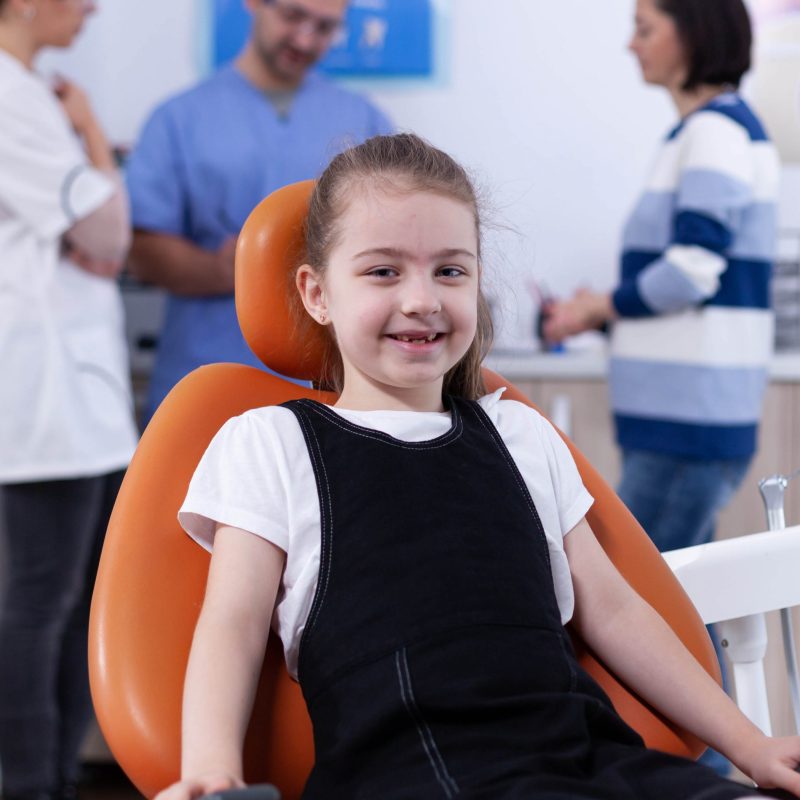 cheerful kid sitting chair dentist office during visit bad tooth treatment parent disscusing with doctor child with her mother during teeth check up with stomatolog sitting chair scaled